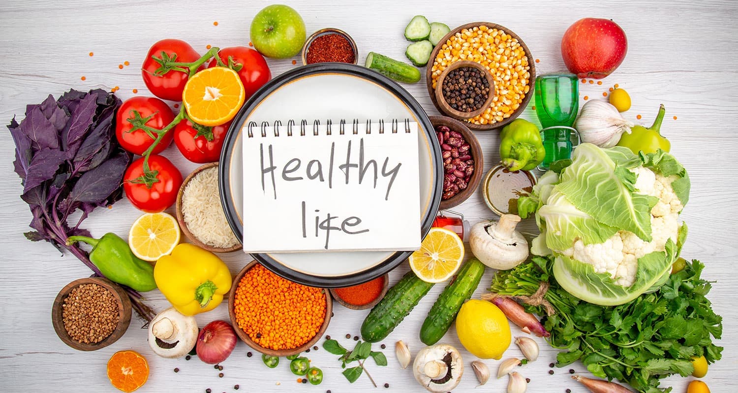 Fresh vegetables, pulses and grains arranged around a plate
